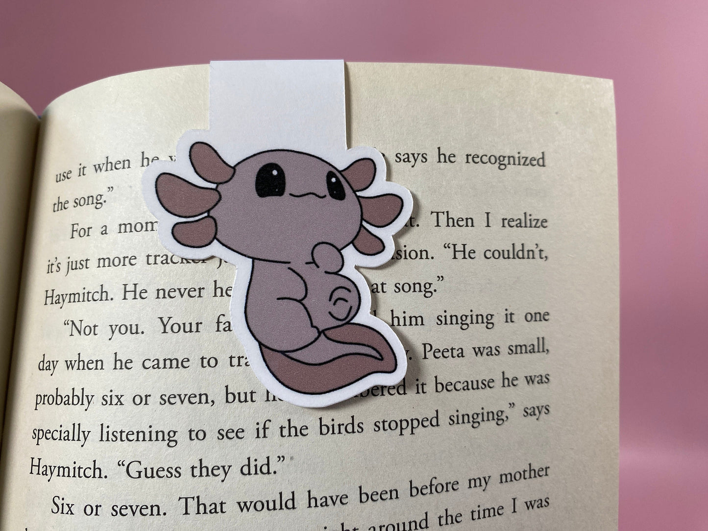 Axolotl-shaped bookmark on an open book with a pink background