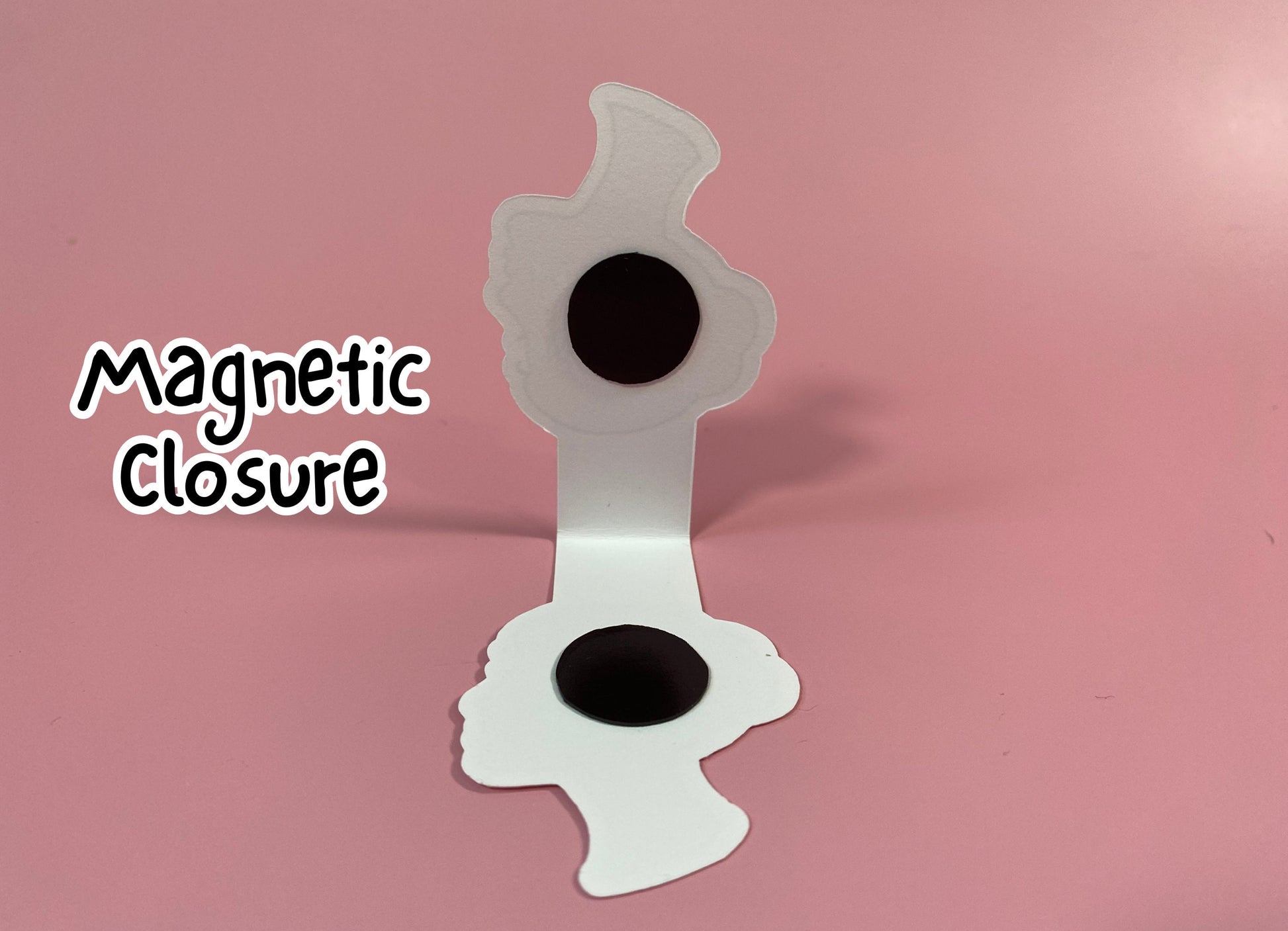Magnetic closure device with two black circular components on a pink background