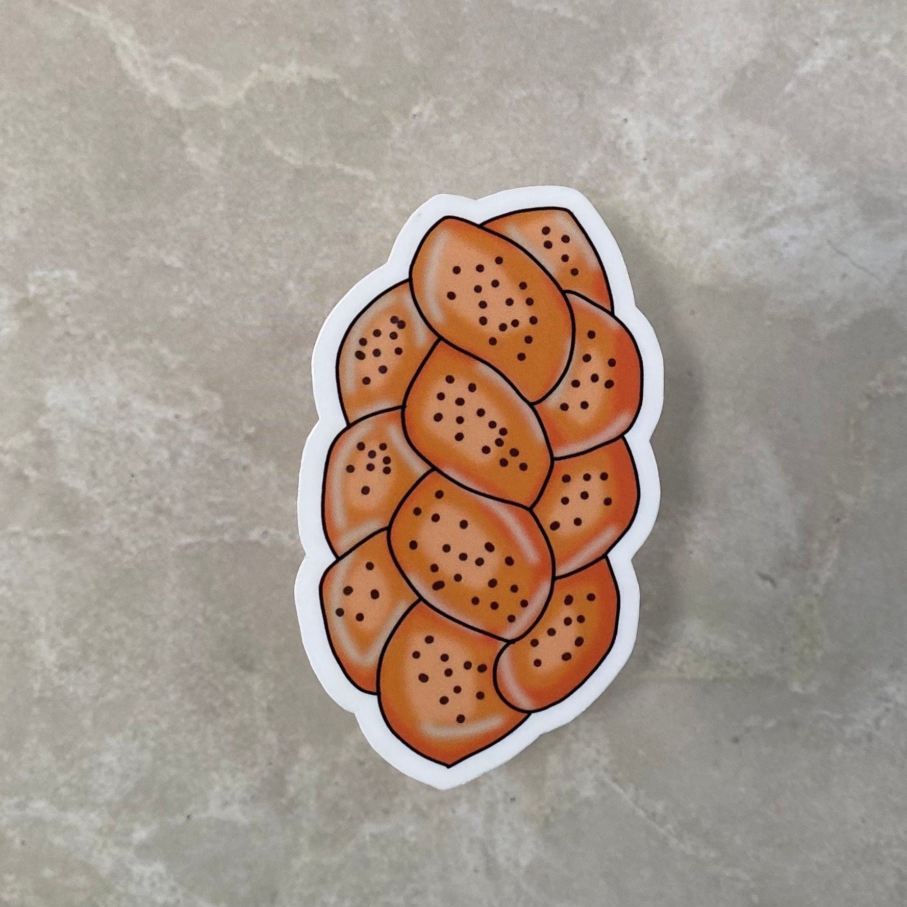 Sticker of a loaf of bread with sesame seeds on a gray surface