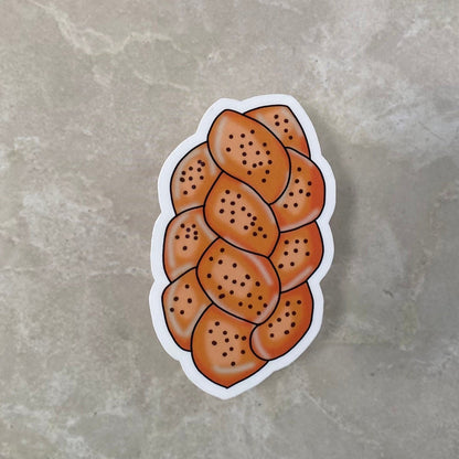 Sticker of a loaf of bread with sesame seeds on a gray surface
