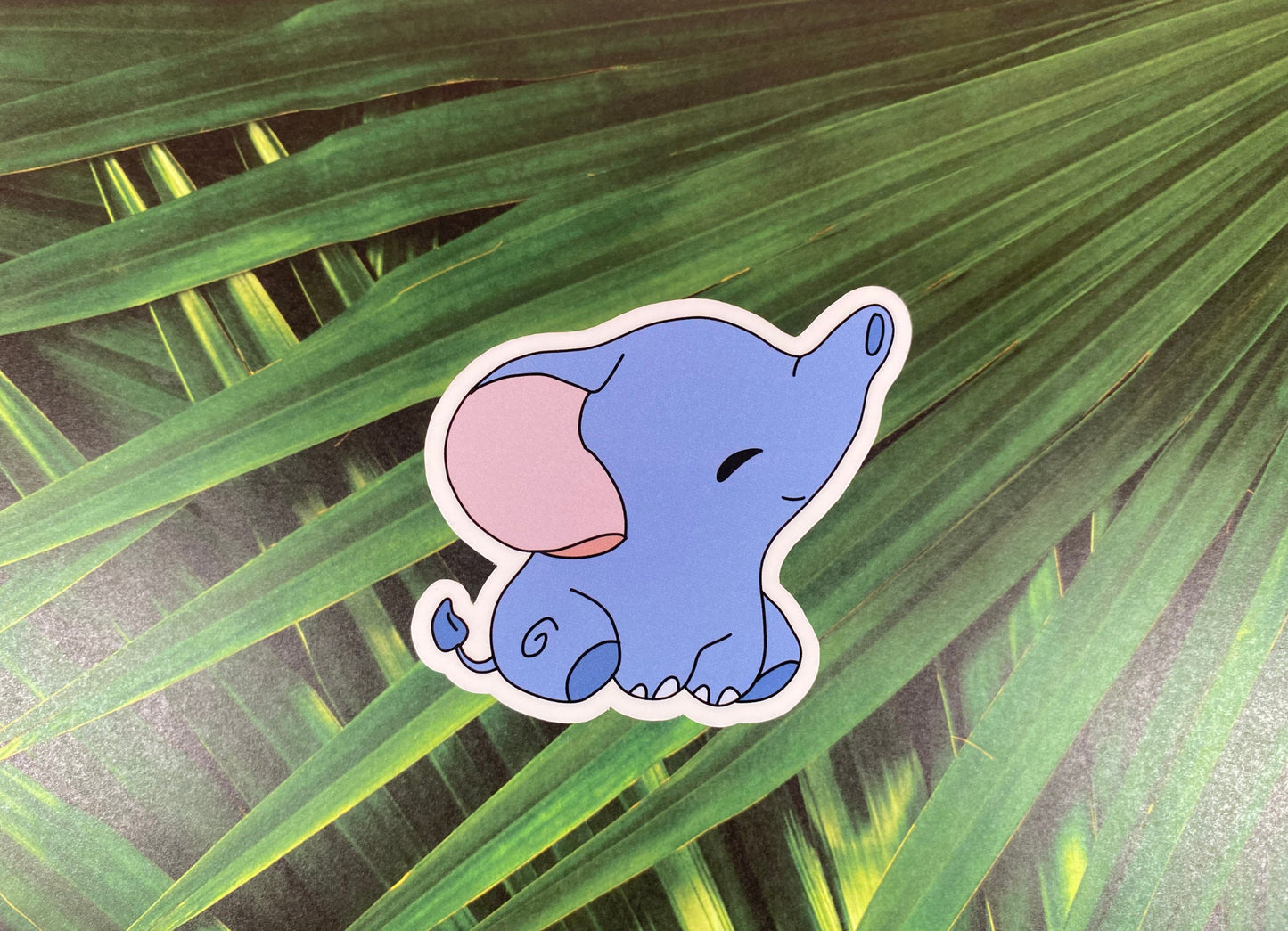 Cartoon elephant sticker on a leafy green background