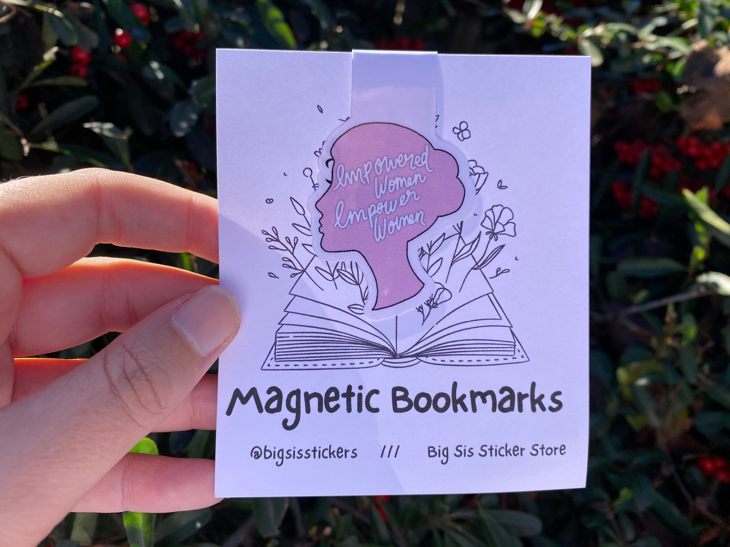 Hand holding a package of magnetic bookmarks with branding text.