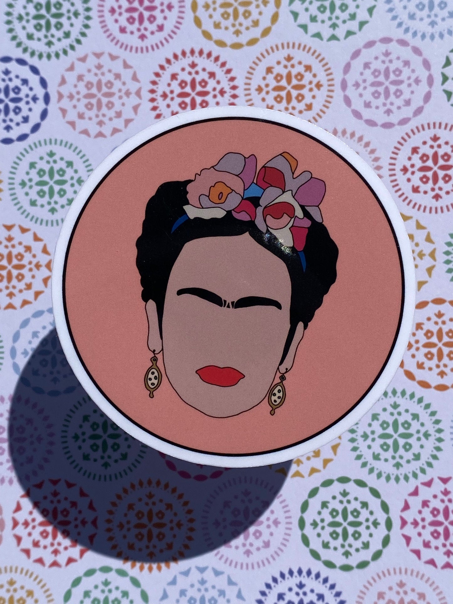 Illustration of Frida Kahlo with floral headpiece on a colorful patterned background