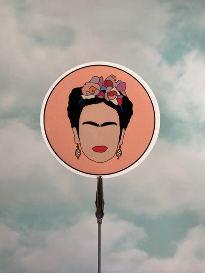 Circular mirror with a portrait of Frida Kahlo with flowers in her hair against a cloudy sky background