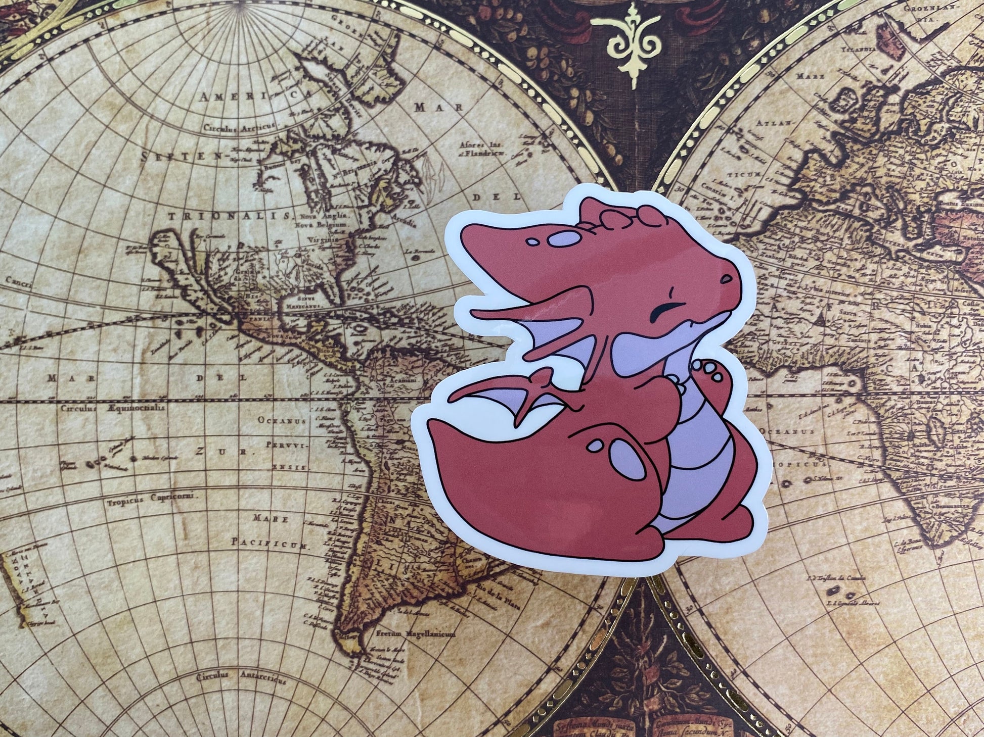 Sticker of a red dragon on an old world map